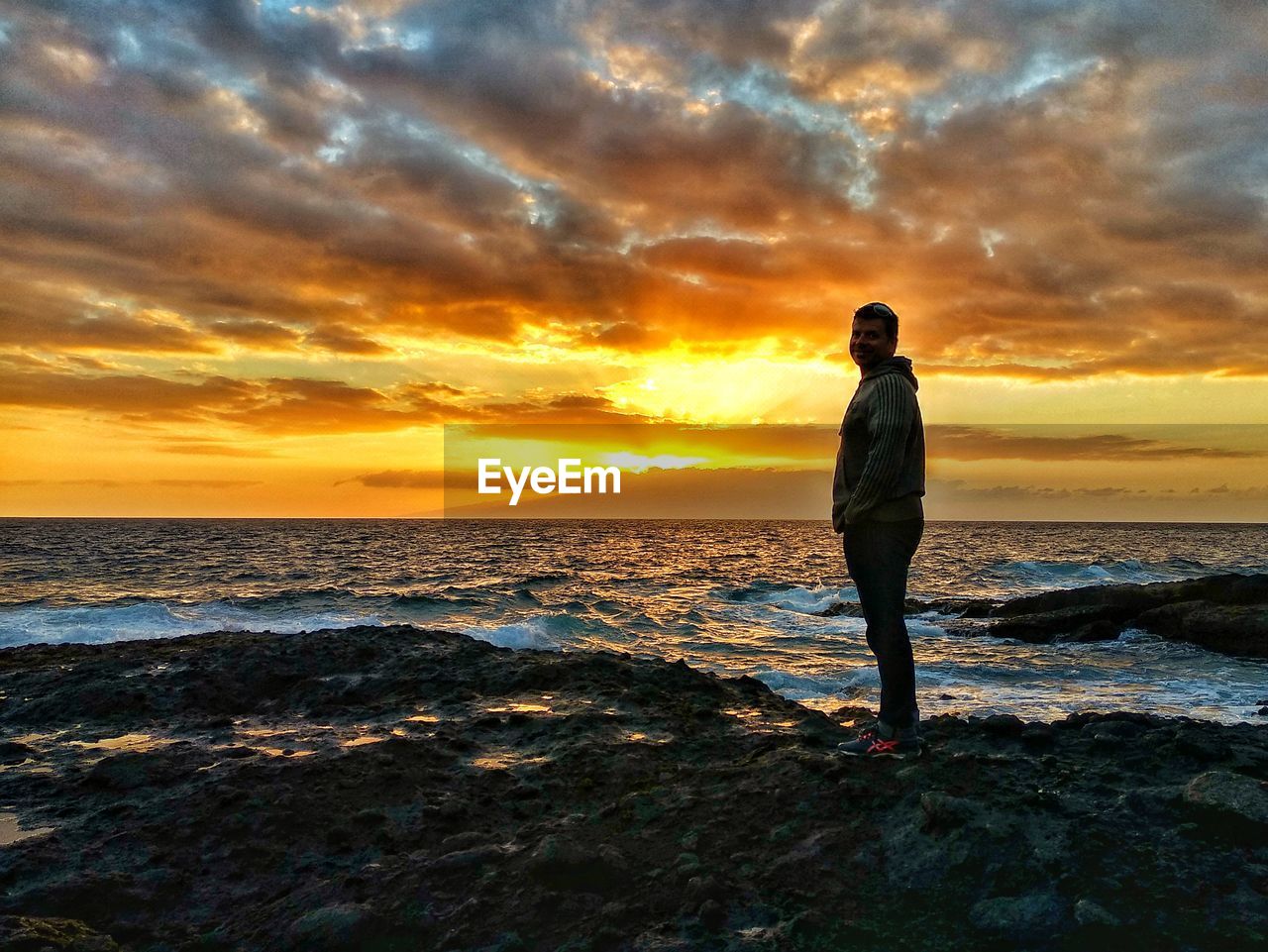 Side view of man standing at beach during sunset