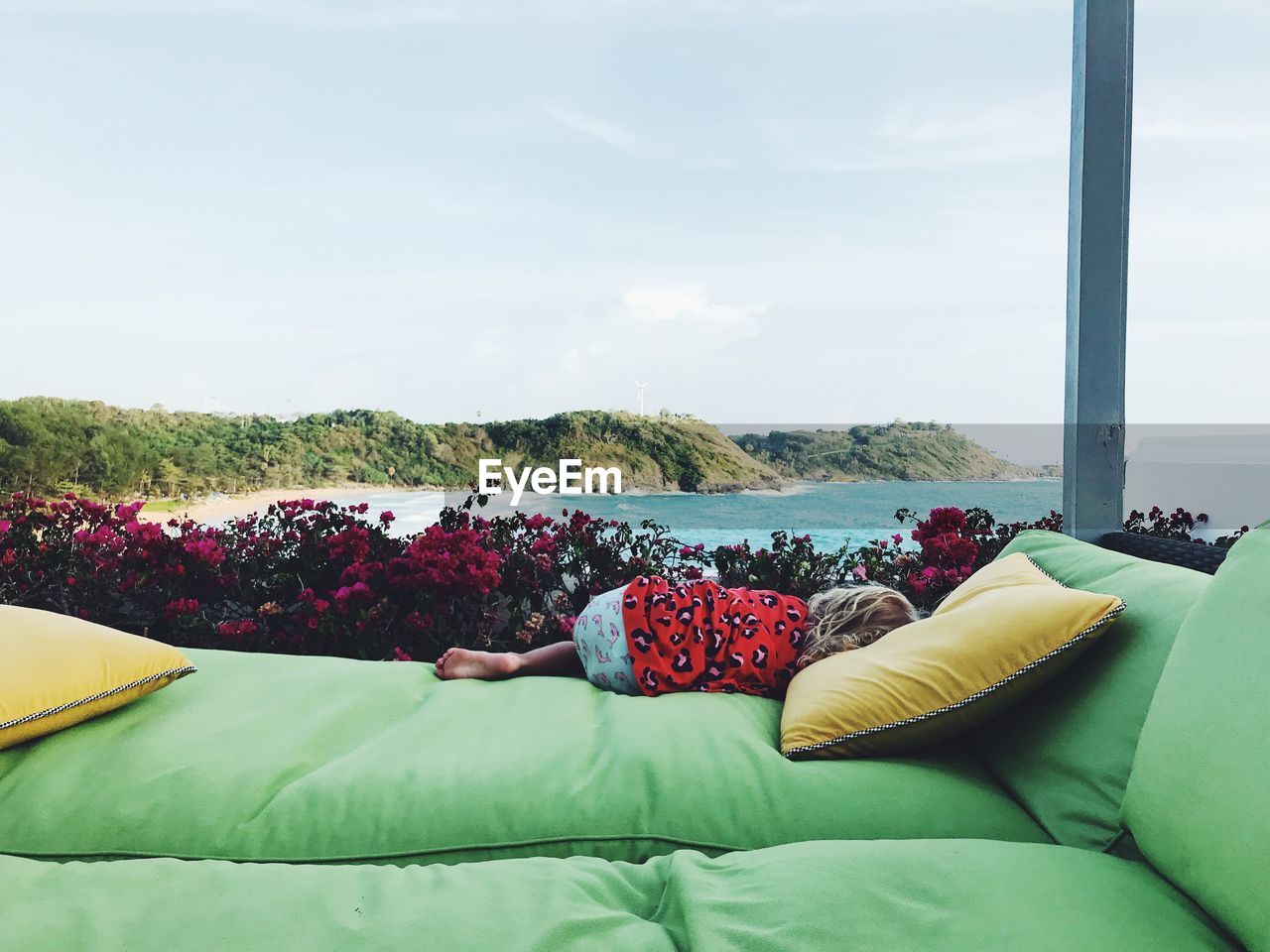 Girl lying on bed against sea