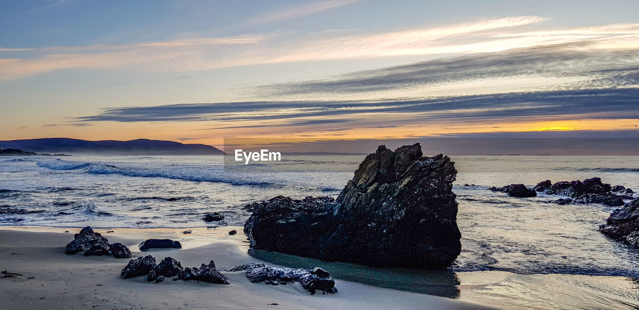 SCENIC VIEW OF ROCKS AT BEACH AGAINST SKY