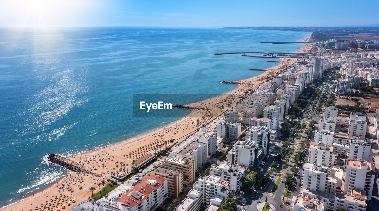 HIGH ANGLE VIEW OF SEA AND BUILDINGS IN CITY