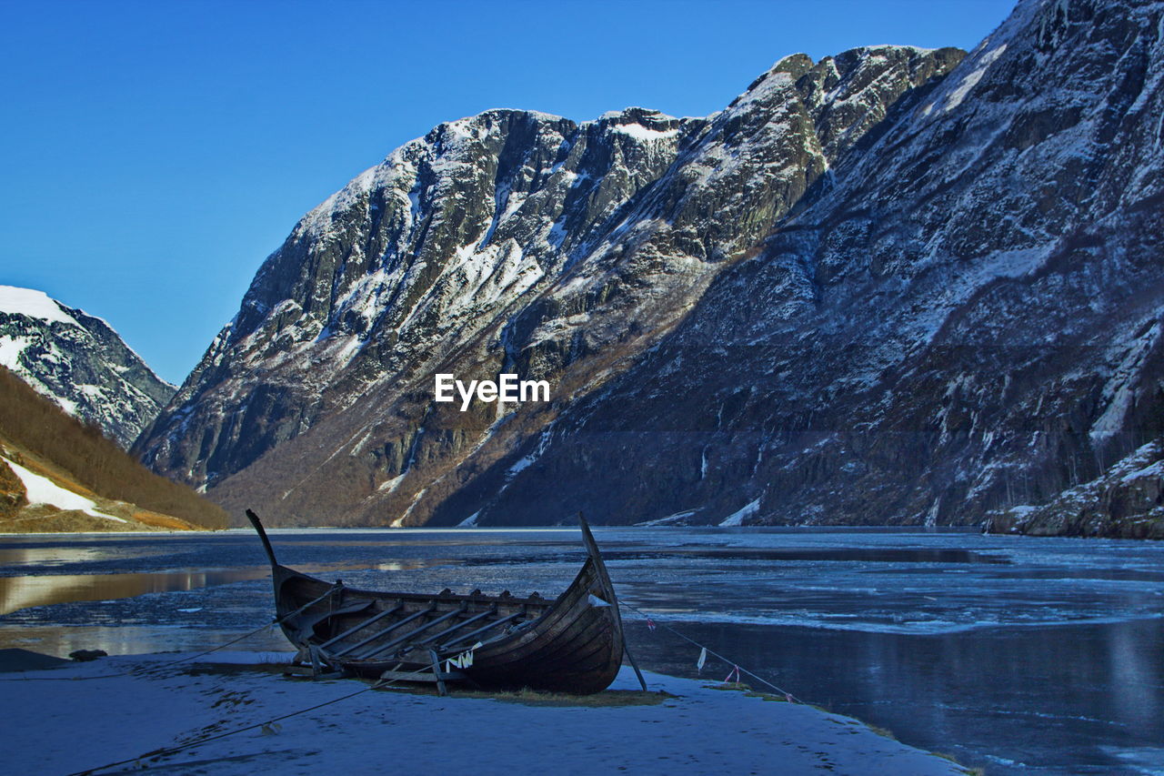 Boat moored at lakeshore against mountain