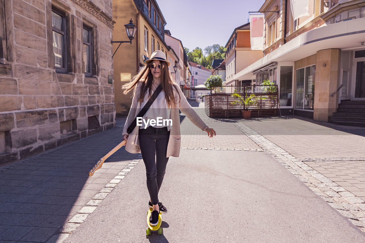 Portrait of teenage girl skateboarding on footpath