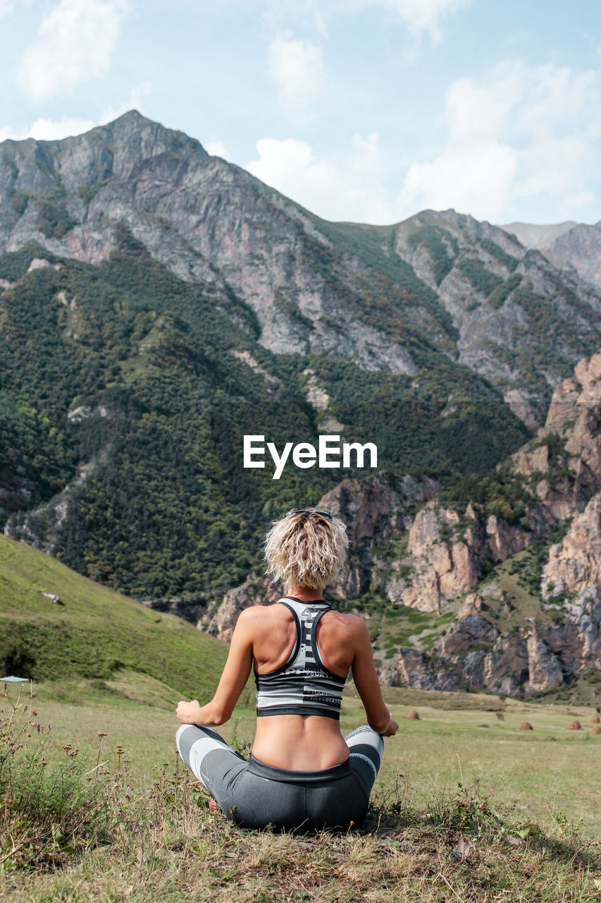 Full length rear view of woman exercising on mountain