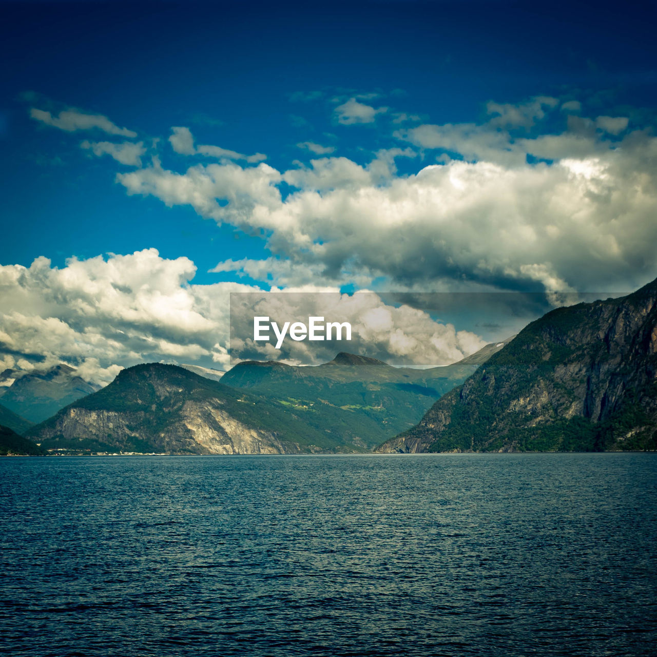 SCENIC SHOT OF CALM SEA AGAINST MOUNTAIN RANGE