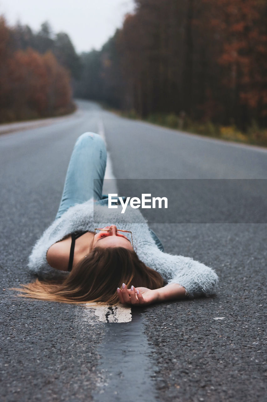 Young woman laying on the empty country road 