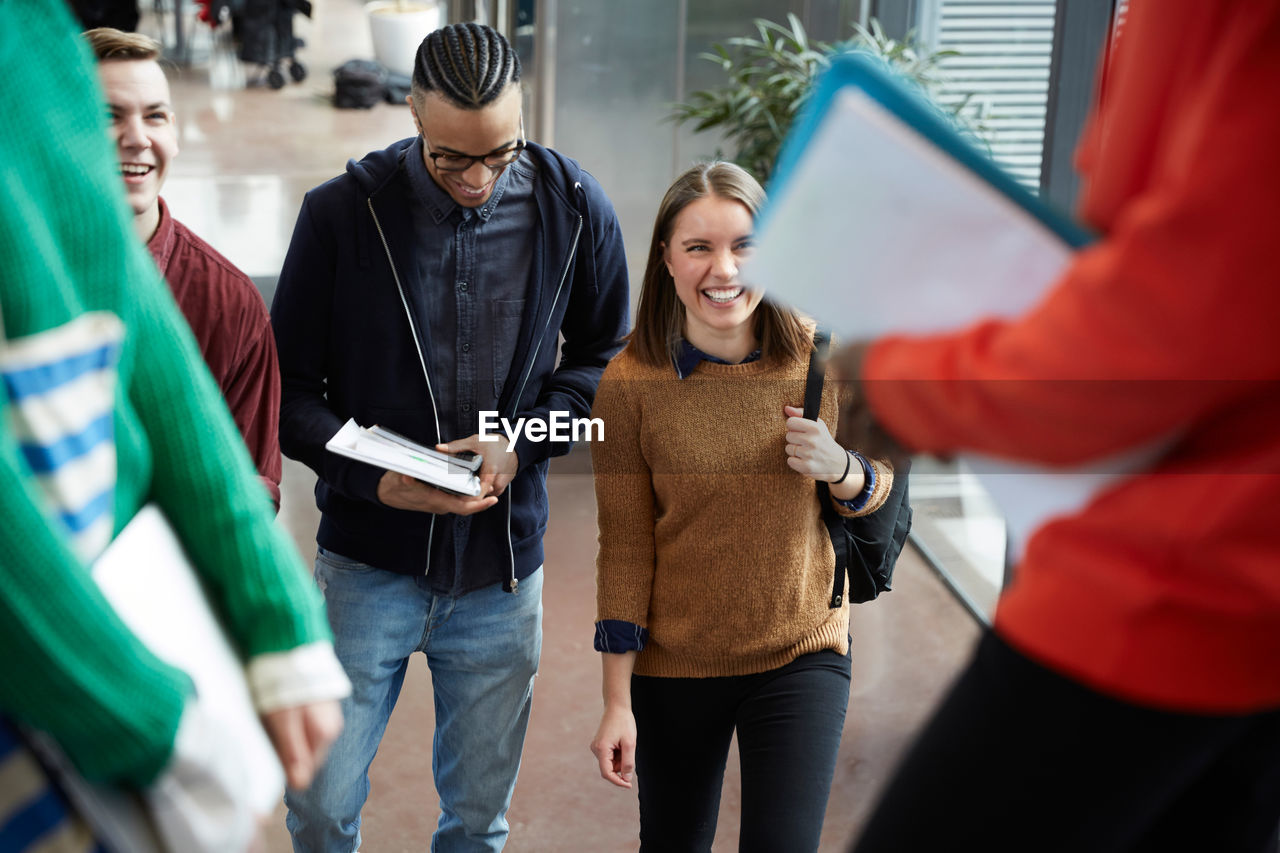 Friends talking to female students standing in university