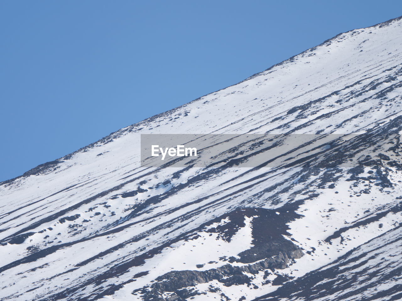 Snow covered mountain against clear blue sky