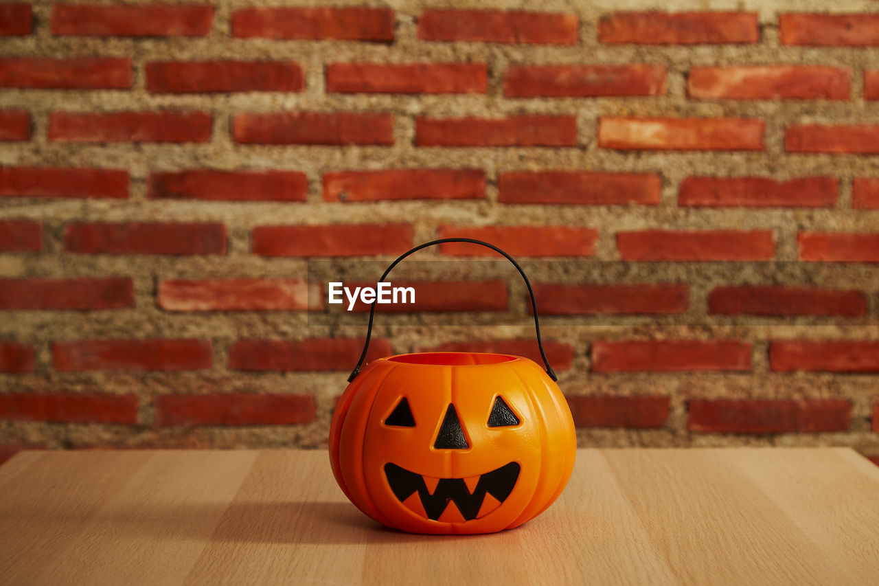 CLOSE-UP OF PUMPKIN ON TABLE AGAINST BRICK WALL