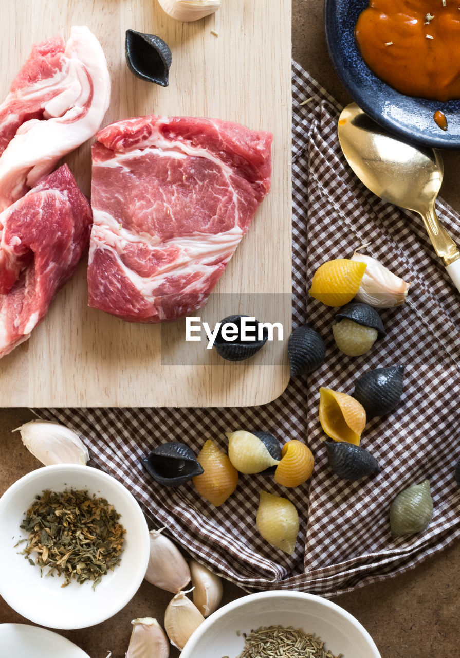 Directly above shot of meat and conchiglie pasta with ingredients on kitchen counter