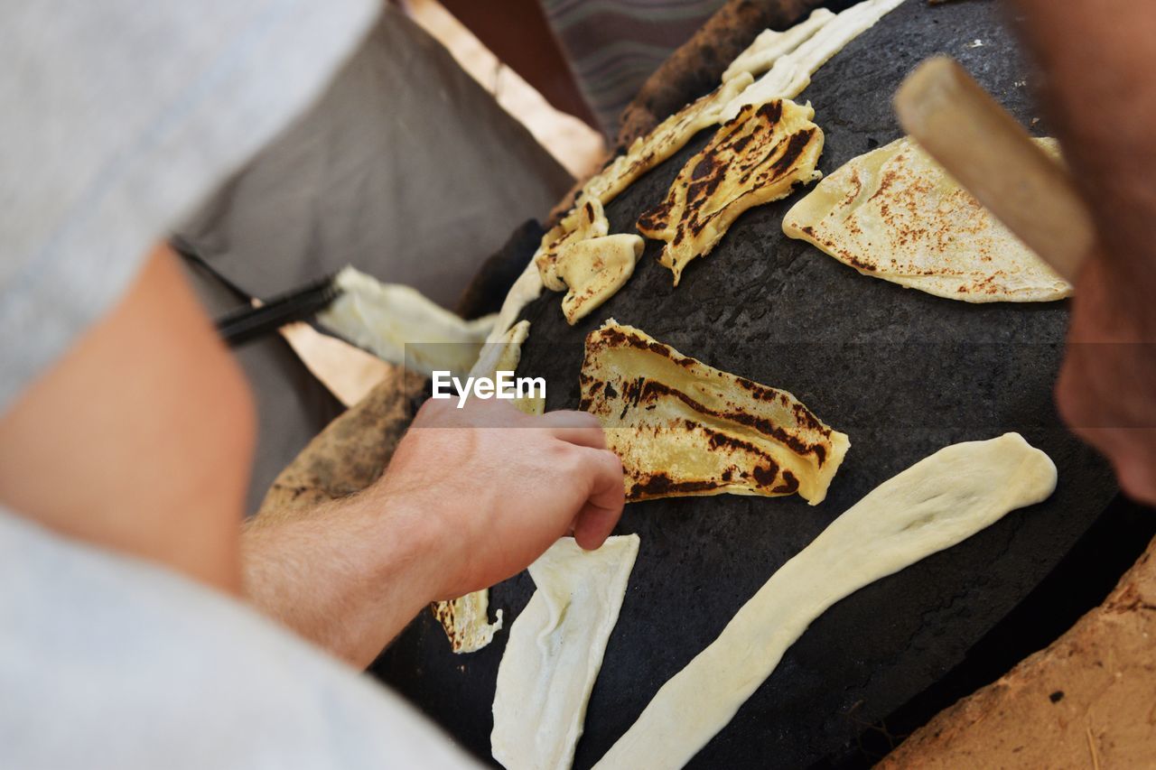 HIGH ANGLE VIEW OF MAN PREPARING FOOD ON CUTTING BOARD