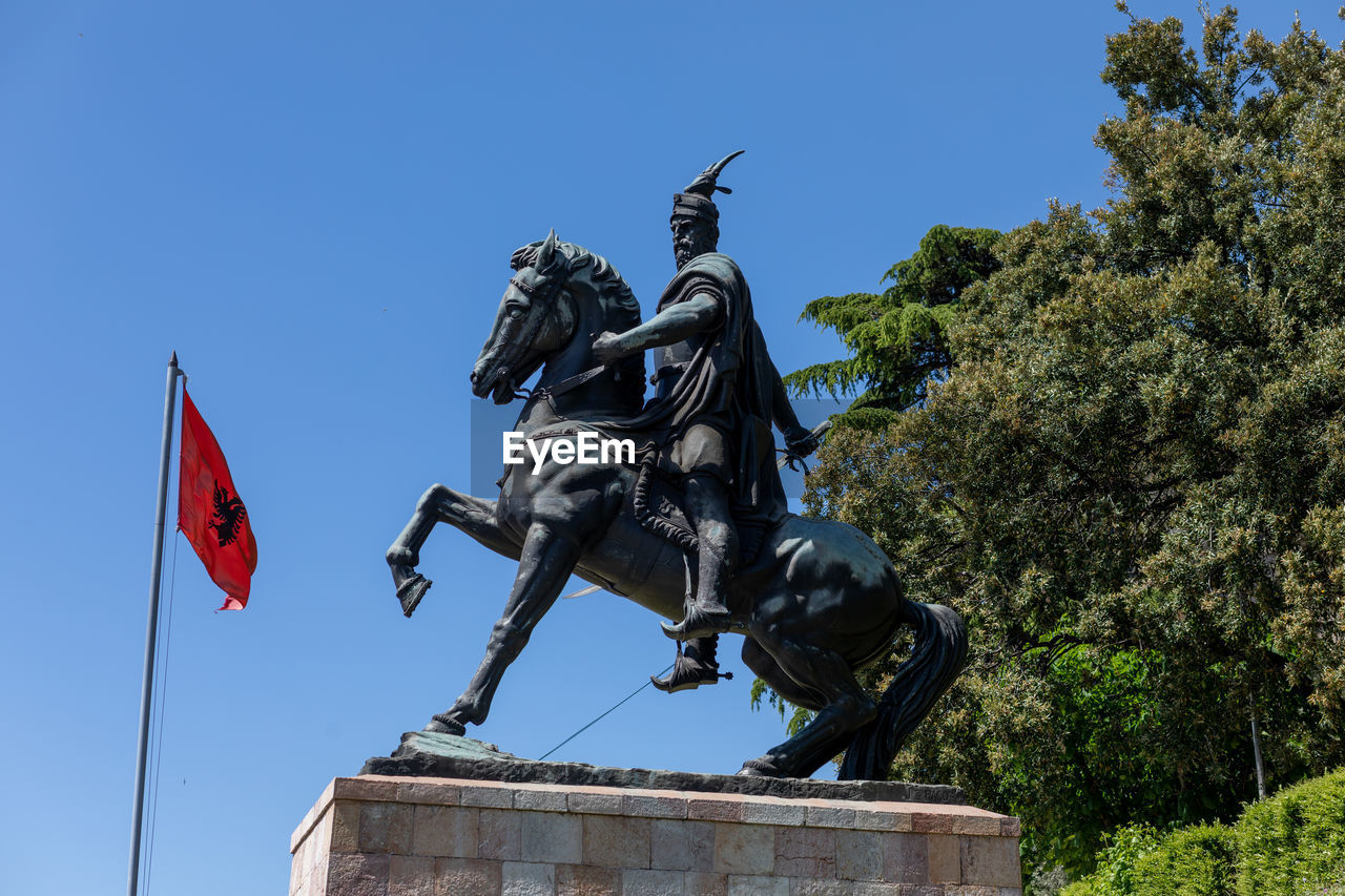 LOW ANGLE VIEW OF STATUE AGAINST TREES AGAINST SKY