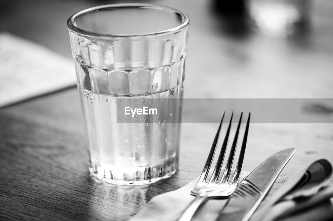 Close-up of glass with drinking water by fork on table