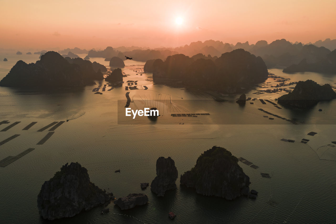 Rocks in sea against sky during sunset