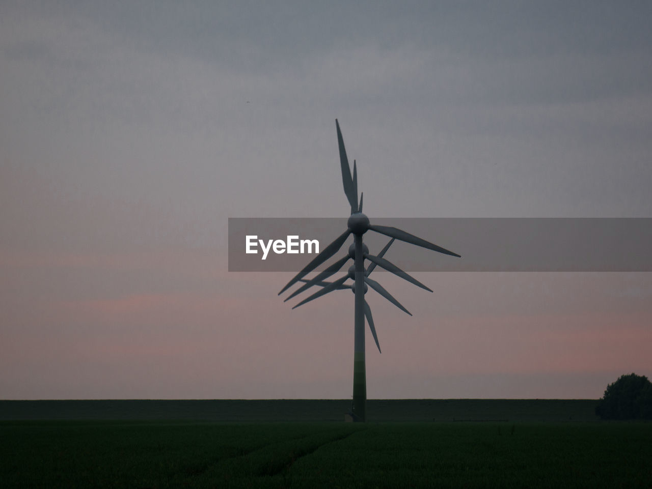 WINDMILLS ON FIELD AGAINST SKY DURING SUNSET