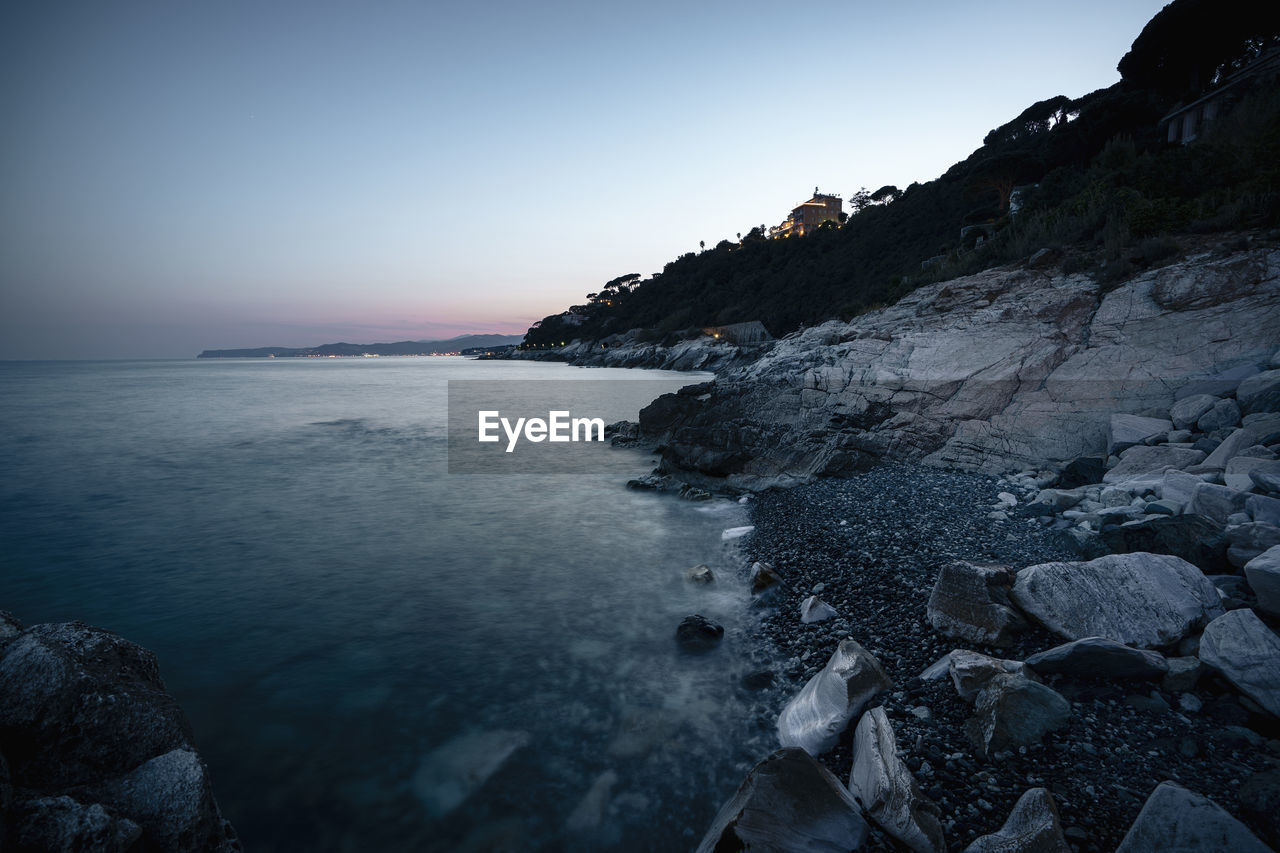 ROCKS ON BEACH AGAINST CLEAR SKY