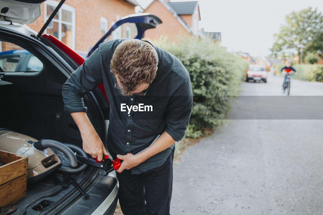 Man standing near open car boot