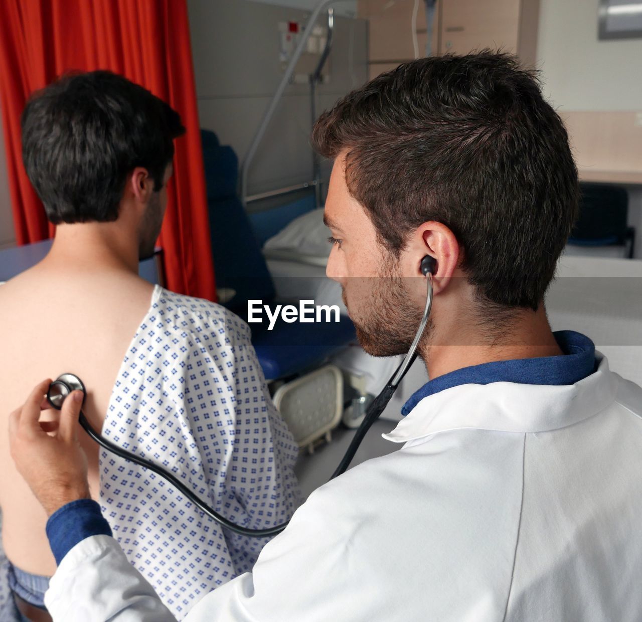 High angle view of doctor checking man with stethoscope in hospital