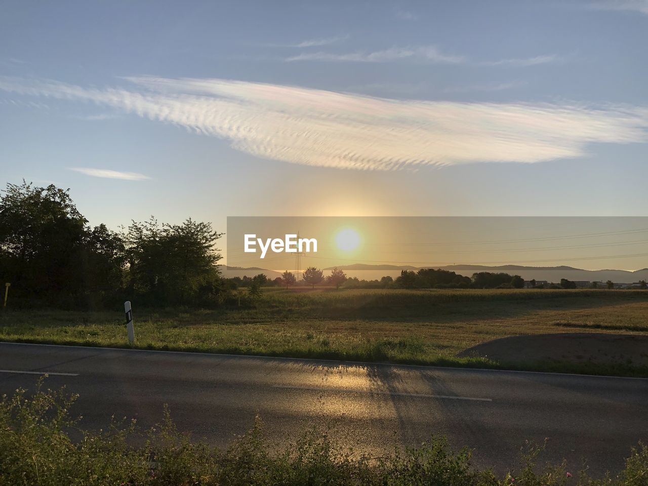 ROAD AMIDST FIELD AGAINST SKY AT SUNSET