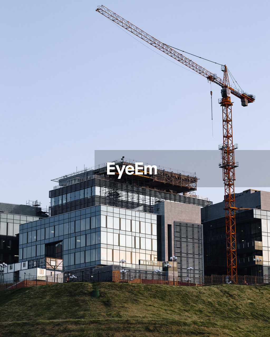 LOW ANGLE VIEW OF CRANE BY BUILDING AGAINST SKY