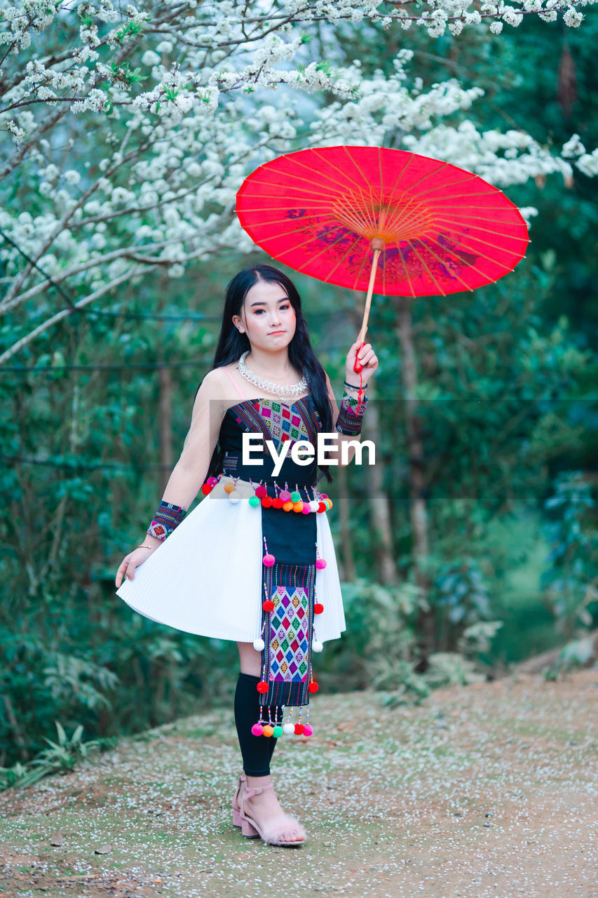 Woman holding umbrella while standing outdoors