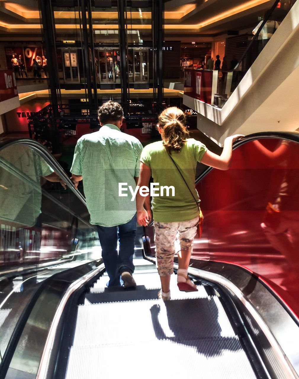 Rear view of father and daughter walking on escalator in boulevard berlin