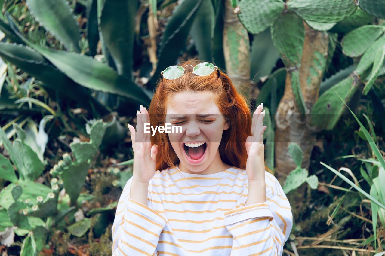 Woman gesturing while shouting against plants