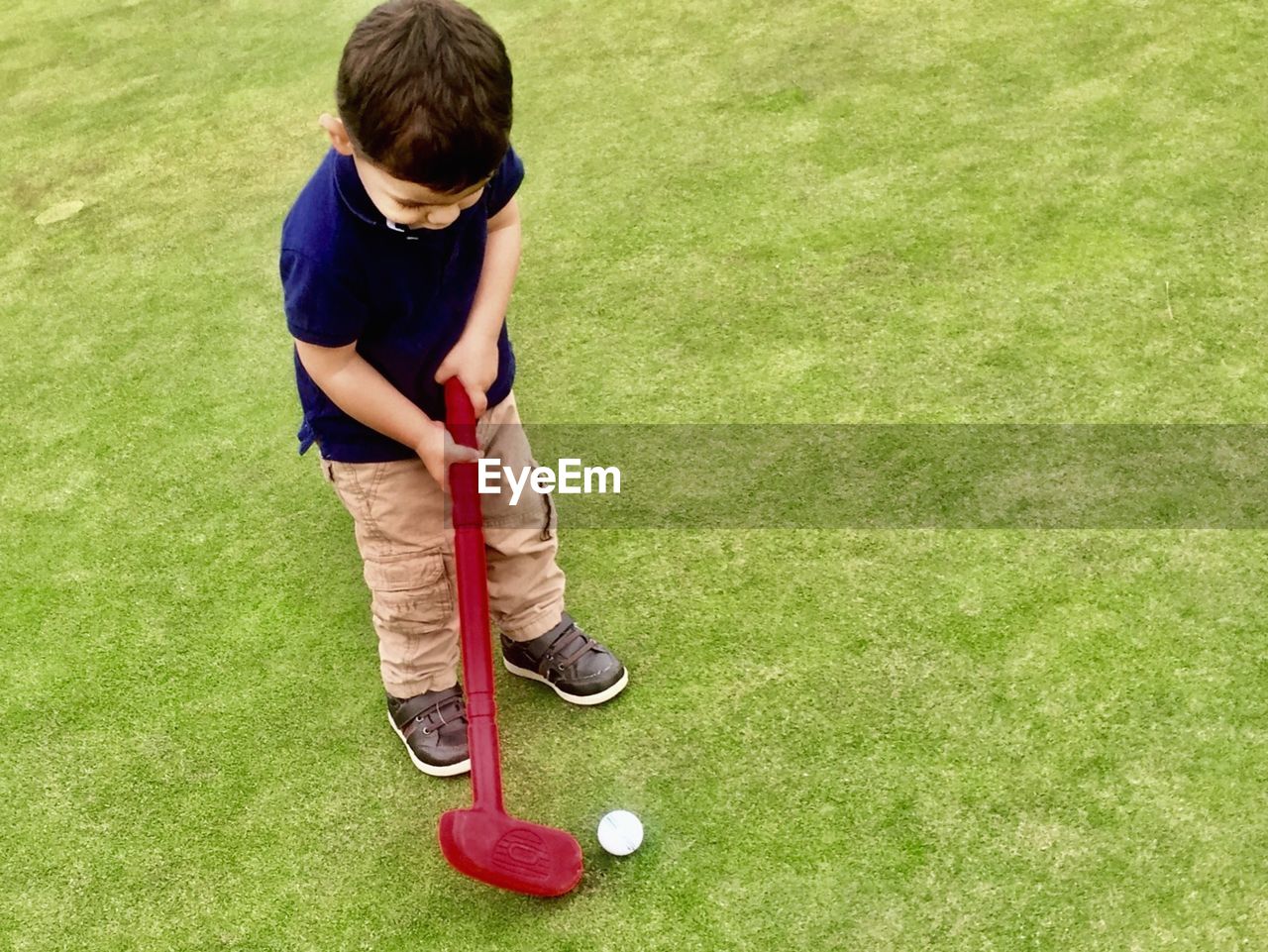 High angle view of boy playing miniature golf on field