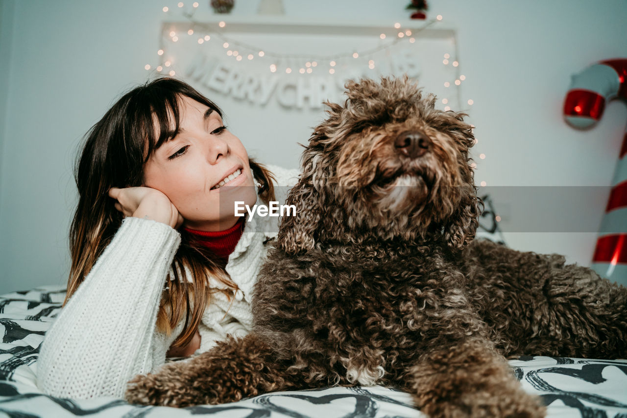 Smiling woman relaxing with dog on bed at home