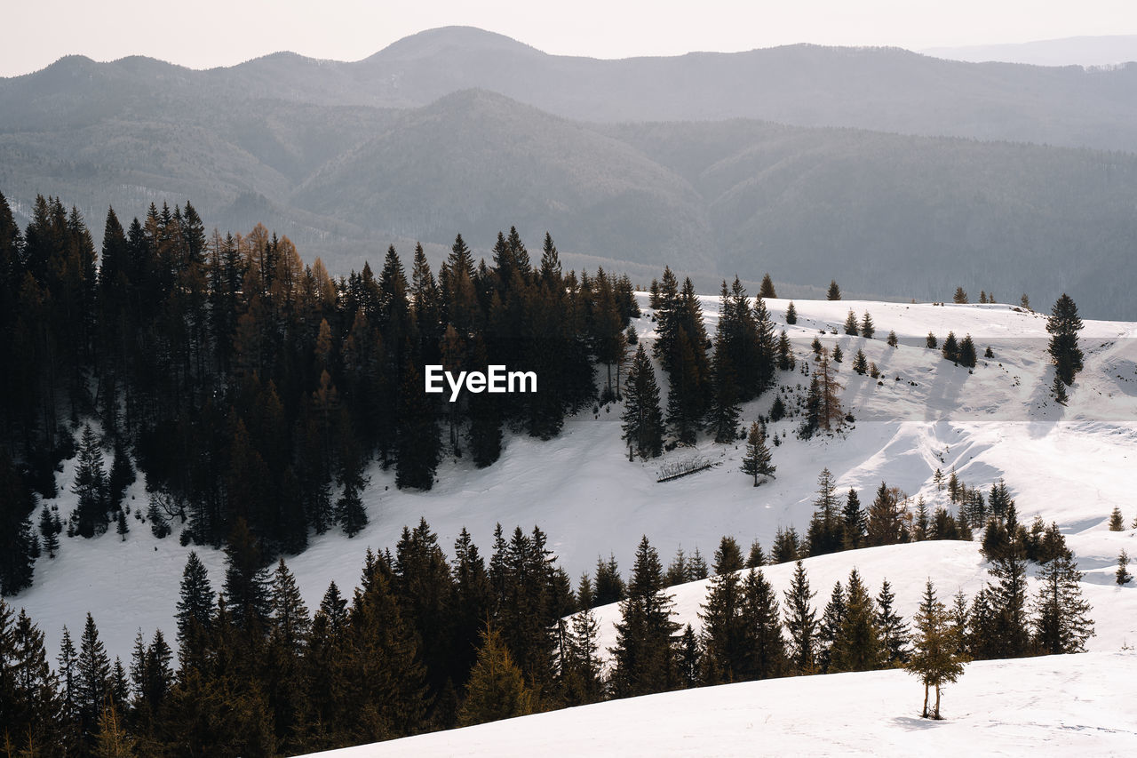 Scenic view of snow covered mountains and cabin against sky