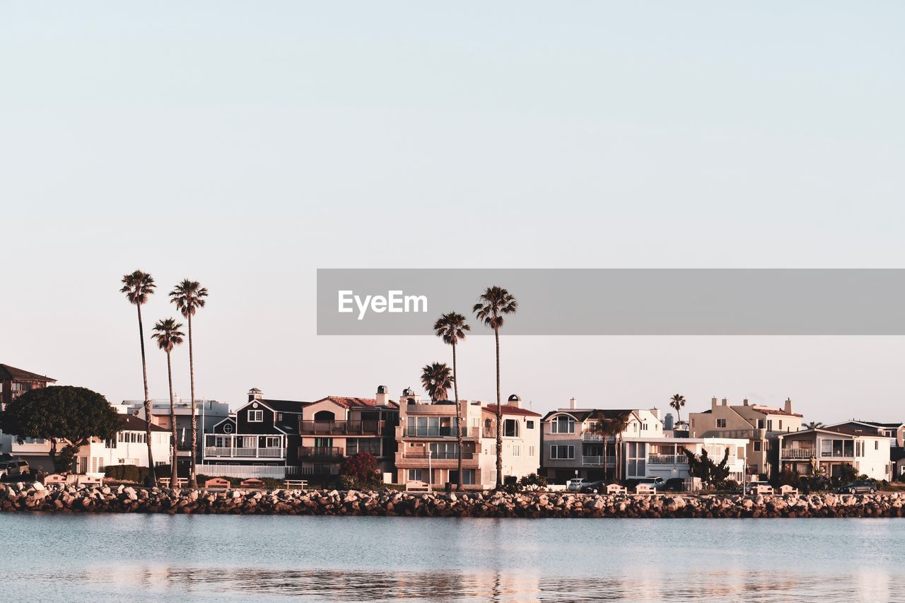 Buildings by sea against clear sky