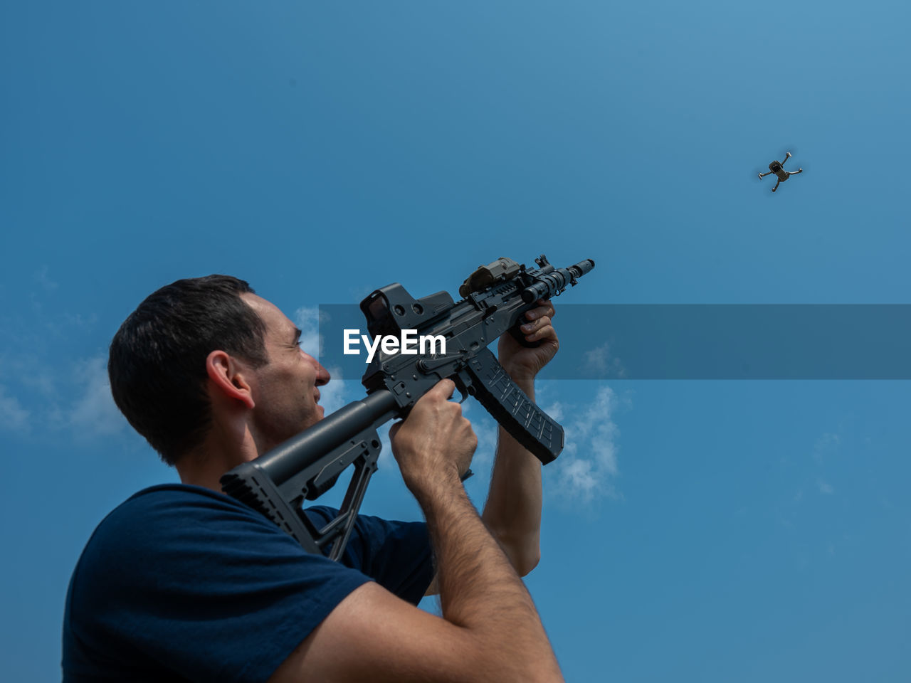 low angle view of man holding camera against clear sky