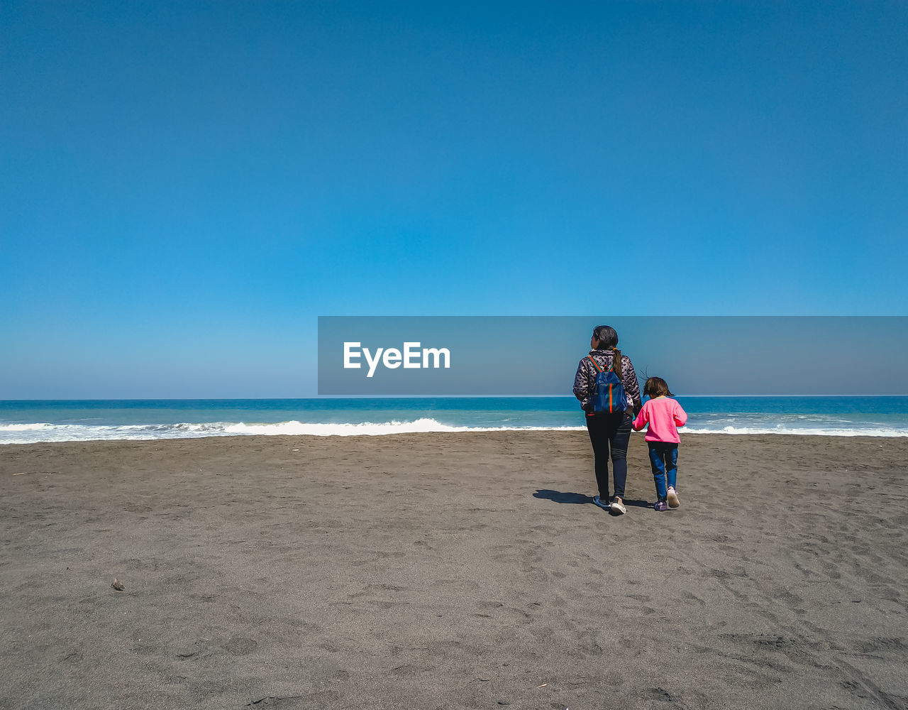 Couple on beach against blue sky