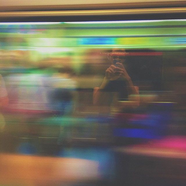 BLURRED MOTION OF WOMAN WALKING IN ILLUMINATED TUNNEL