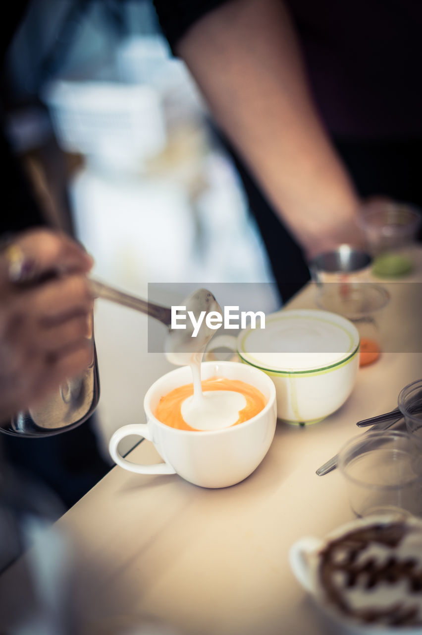 High angle view of barista mixing milk in drink at cafe