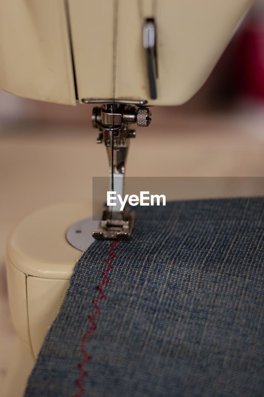 Sewing machine close up sewing blue jeans denim.
