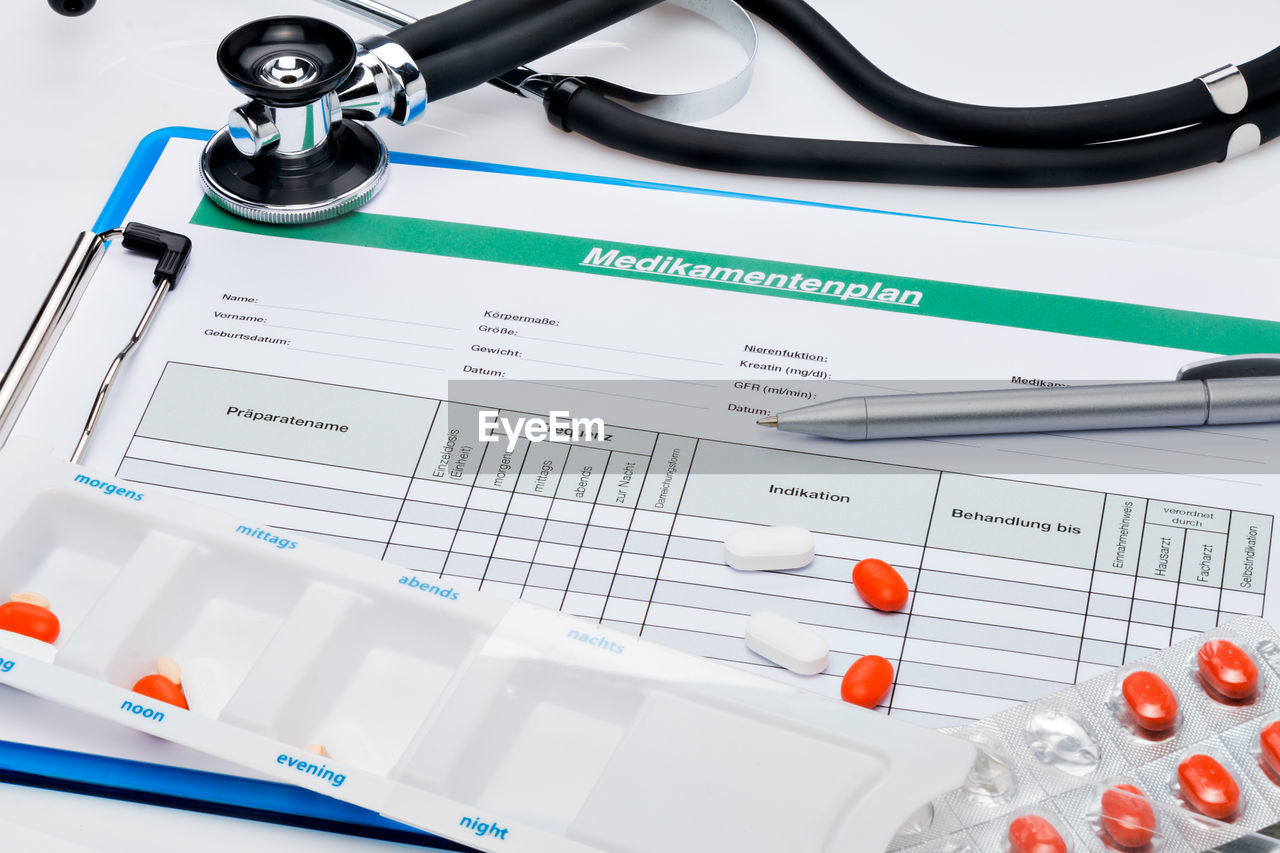 Pills and stethoscope on medication plan at table