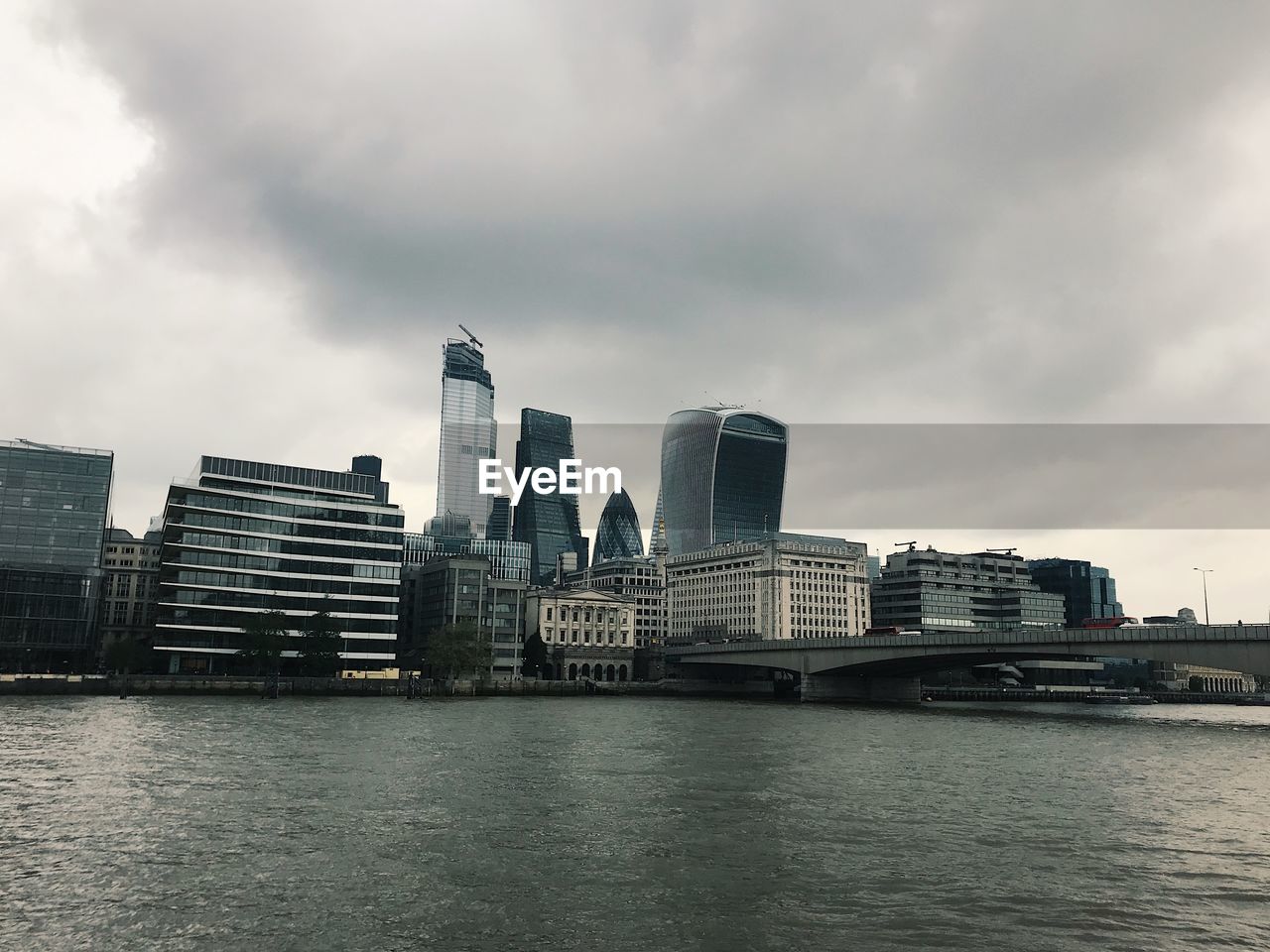 Modern buildings by river against sky in city
