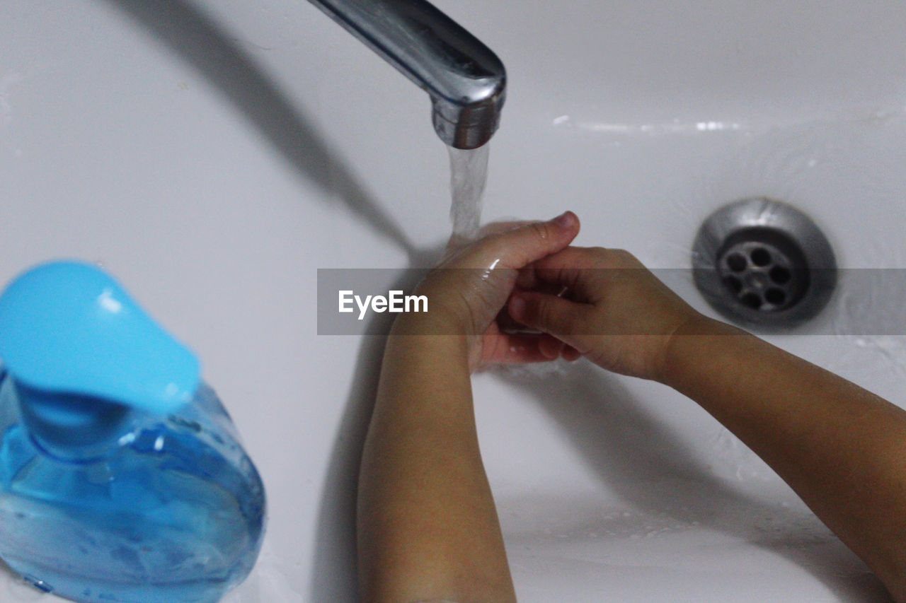 Cropped image of child washing hands in sink