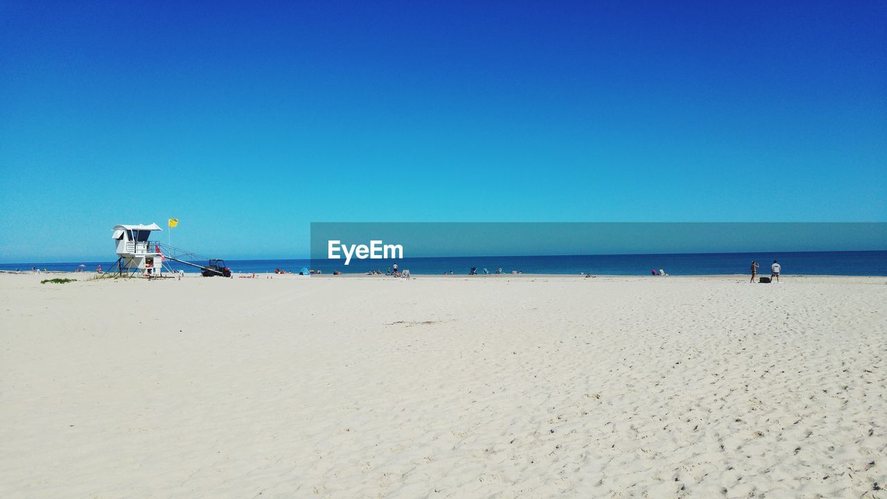 Scenic view of beach against clear blue sky