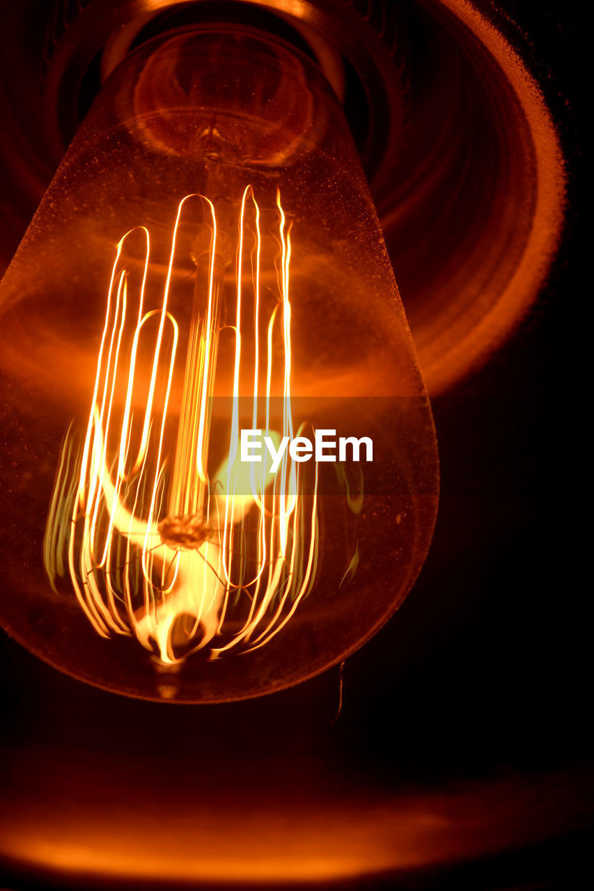 Close-up of illuminated light bulb in darkroom