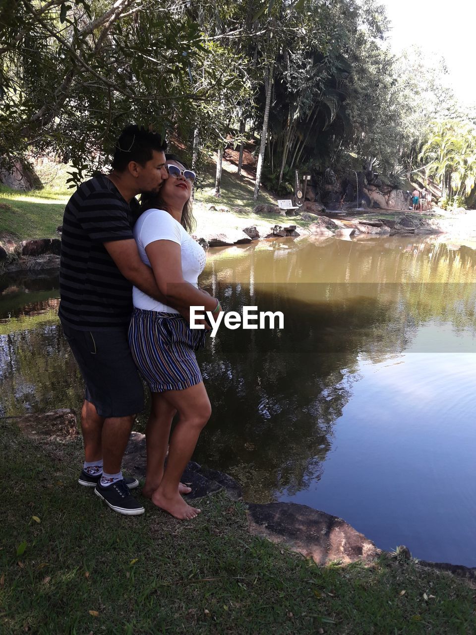 REAR VIEW OF COUPLE STANDING BY LAKE