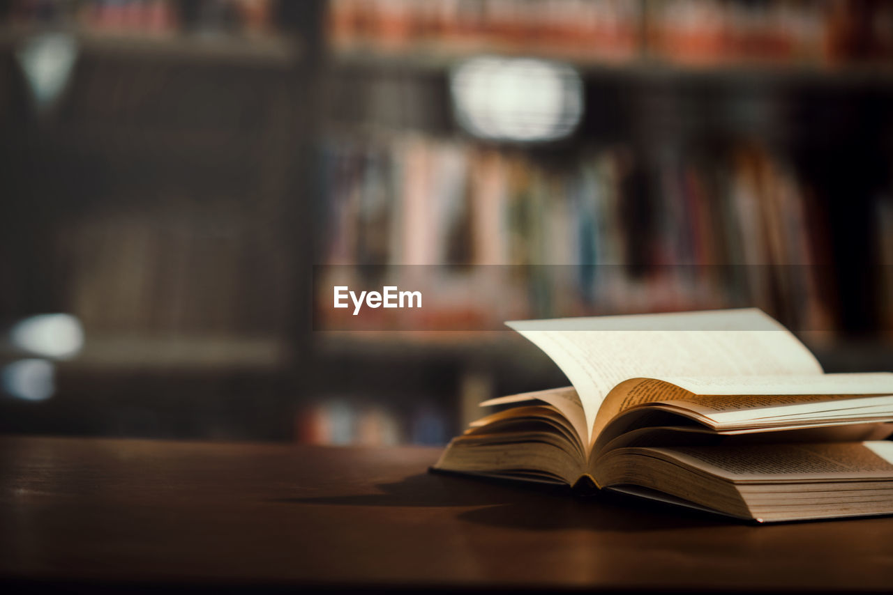 Book on table against shelf in library 