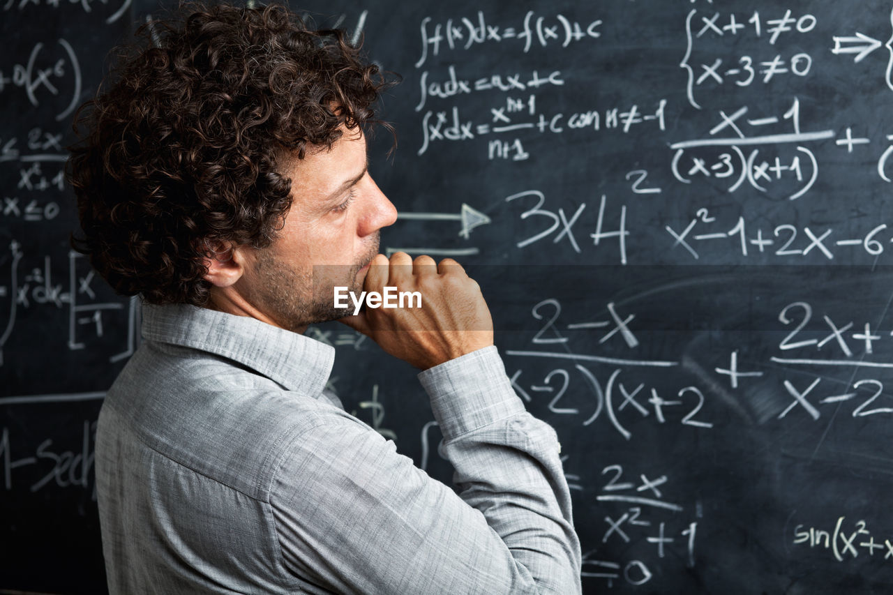 Teacher looking at blackboard in classroom