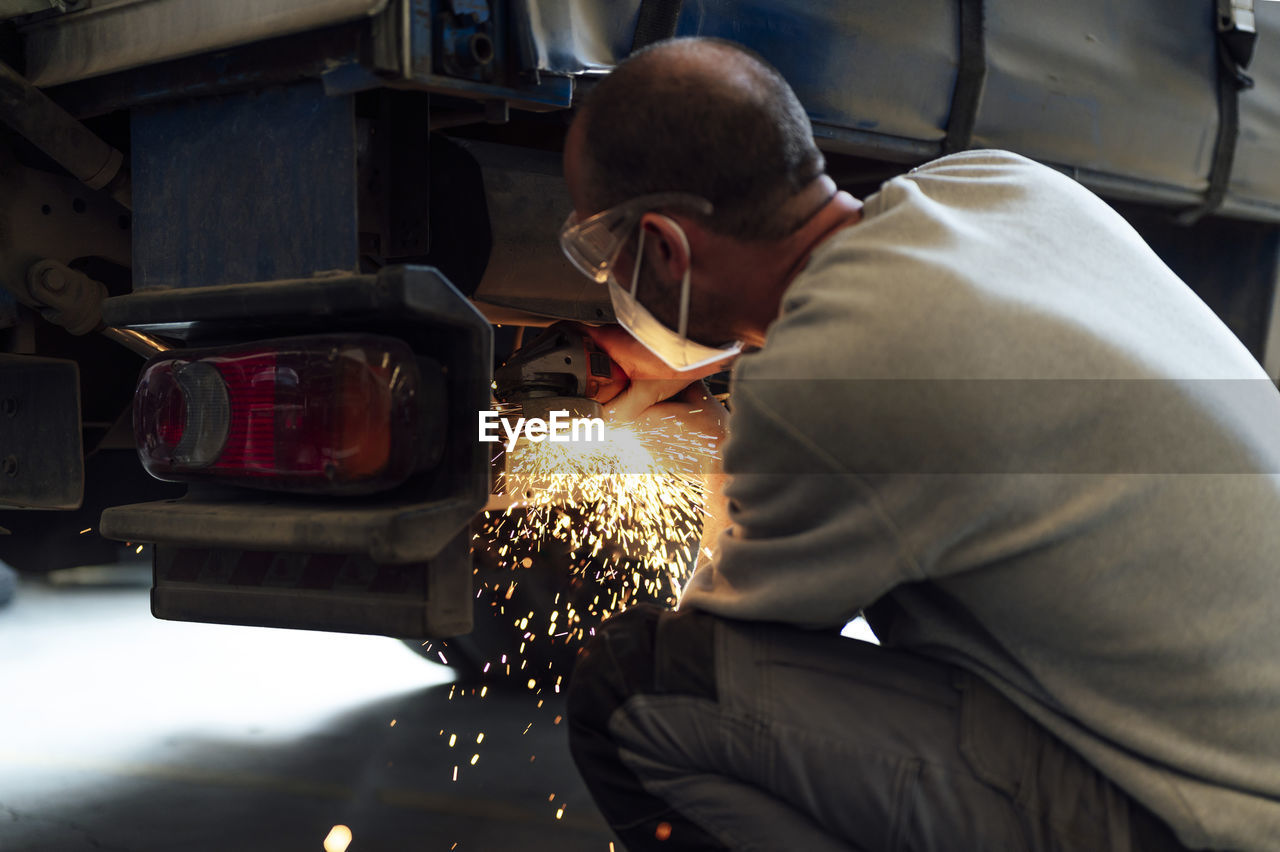 Auto expert cutting metal of car in workshop