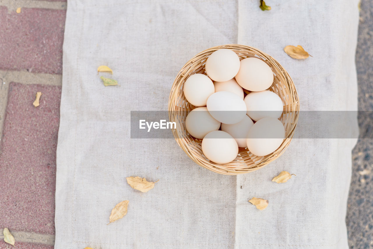 HIGH ANGLE VIEW OF EGGS IN BASKET ON WOOD