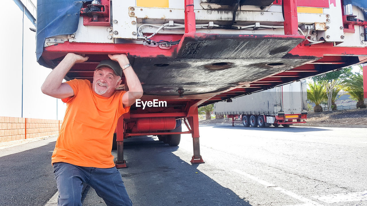 Portrait of senior man carrying truck on road