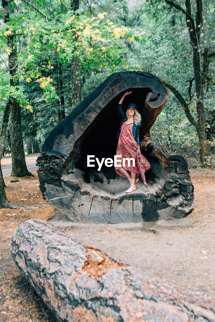 WOMAN SITTING ON TREE STUMP