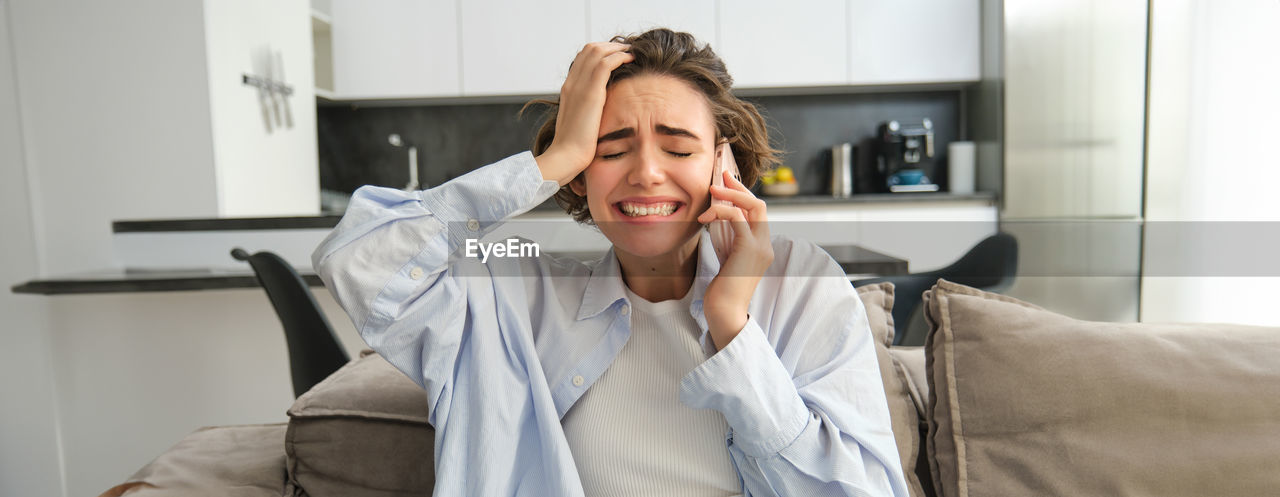 portrait of young woman using mobile phone while sitting at home