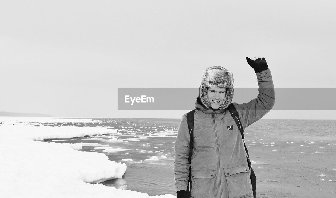 Smiling young man standing on snowy shore