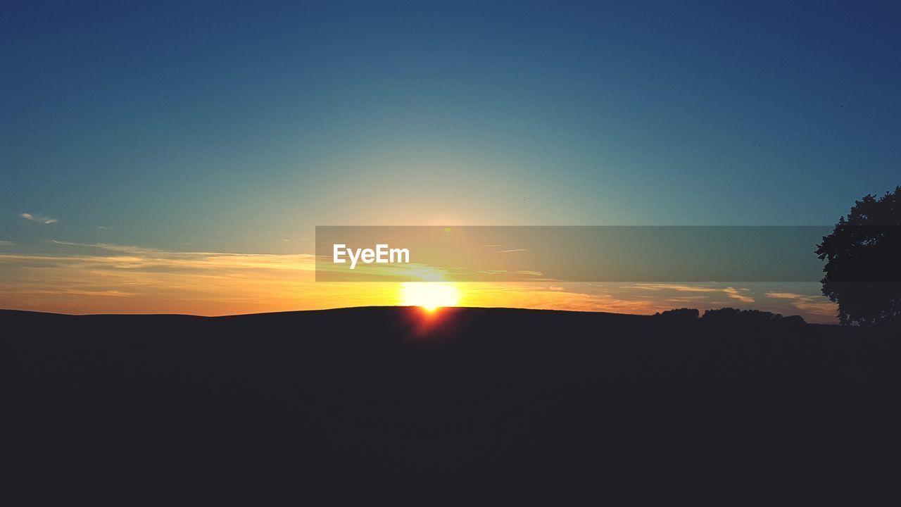 SILHOUETTE LANDSCAPE AGAINST CLEAR SKY AT SUNSET